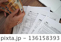 Self-employed man scrupulously counts money sitting at table with uncompleted W-4 1040 and W-9 tax declarations office documentation concept slow motion 136158393