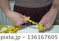 Measuring fabric for sewing projects in a cozy crafting space with hands and tape measure 136167605