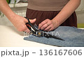 Hands using cutting scissors to cut denim fabric 136167606