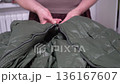 Man's hands fasten and unzip a down jacket 136167607