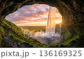 Majestic waterfall view from inside cave during vibrant sunset nature landscape 136169325
