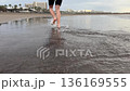 Barefoot runner jogging along wet sandy beach with mirror reflection, calm ocean and cloudy sunrise sky. Healthy outdoor cardio workout, travel resort coastline background. 136169555