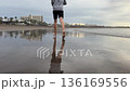 Barefoot runner jogging along wet sandy beach with mirror reflection, calm ocean and cloudy sunrise sky. Healthy outdoor cardio workout, travel resort coastline background. 136169556
