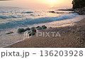 Sunset over the Adriatic Sea on Makarska beach, Croatia, summer coastline with waves, pebbled shore and warm evening light, popular travel destination and seaside vacation atmosphere. 136203928