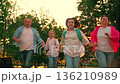 Family, laughter, joy. Parents with their children daughters having fun playing running in park. Happy family. Concept parenting. Family in city park. Mom dad kids run to school on city street lesson. 136210989