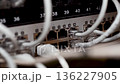 Server room rack with network cables. Network cables connect to server rack ports with blurry bokeh lights in the background. A close-up of a network rack with multiple Ethernet cables connected to it 136227905