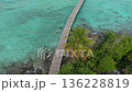 Aerial view of a tropical island in the Maldives, featuring a serene wooden pier and lush palm trees 136228819