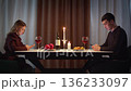 Couple with cell mobile phone addiction having evening wine dinner together. People celebrating event. Awkward ignore romantic first date problem at restaurant or home. Holiday candle light atmosphere 136233097