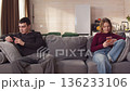 Sad ignore couple sit couch at home using smartphone. Addiction social media digital technology, relationship coldness issue. Cell mobile phone scrolling problem. Useless cellphone internet surfing. 136233106