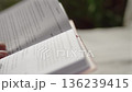 Close-up, a woman's hand turning a page of a book while reading while sitting at a table 136239415