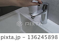Contemporary bathroom scene: water flowing from a modern faucet during handwashing, showcasing minimalist design and smooth operation for daily hygiene routines. 136245898