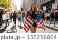 Woman happily holds waves American USA flag, proudly showing patriotic emotion or supportive attitude. Caucasian girl demonstrates cheerful national pride and enthusiasm, isolated on gray background 136256804