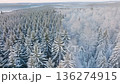 Stunning Aerial Views of a Snow-Covered Forest Landscape in Winter, Highlighting the Peaceful Serenity of Snow-Laden Pines and Frosted Foliage Under a Pale Sky 136274915