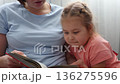 Close up of mother and a Caucasian little daughter are reading a book of fairy tales together. Concept of Mother's Day and preschool education. 136275596