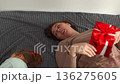 Top view of Caucasian mother and daughter holds a gift for the holiday together and lying on bed. The concept of preschool education and Valentine's Day. 136275605