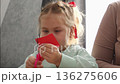 Portrait of a Caucasian cute little girl cutting a heart out of red paper. Pre-school children's education. 136275606