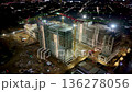 Aerial view of a nighttime construction site with high-rise buildings and operating cranes in the city 136278056