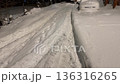 Quiet residential street and parked cars completely covered in a thick blanket of fresh snow after a heavy winter storm at night, creating a serene and frosty urban winter wonderland scene 136316265