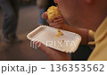 Man eating street food pizza from paper plate outdoors. Italian fast food culture, urban lifestyle. Face not visible, anonymous person. 136353562
