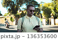 Man using smartphone outdoors in European city street 136353600