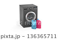 Liquid detergent bottle and washing powder bag in front of a black modern washing machine 136365711