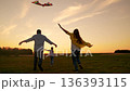 Young family, kid plays with kite in meadow. Happy family plays with kite in park. Father mother run through grass, child dreams flying. Cheerful people play together in nature. Girl kid dreams of fly 136393115