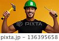 Happy worker holding tools in front of orange background during a building project 136395658