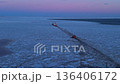 Aerial perspective of freighter slicing through icy waters beneath soft pastel evening sky 136406172