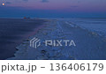 Frosty coastal environment displaying pier stretching to cargo vessel amid rugged ice formations 136406179