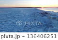 Broad aerial perspective of fractured ice terrain extending into horizon with pastel colored sky 136406251