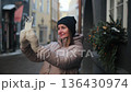 Woman taking selfie in a winter street with decorations in a small town 136430974