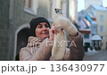 Woman takes a picture with her phone in a city street during daylight hours 136430977