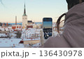 Person holding phone and taking picture of city in winter during sunny day 136430978