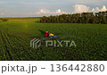 Aerial drone view of tractor spraying crops on green agricultural field with sprayer equipment. Modern farming, agriculture and crop protection concept in countryside landscape  136442880
