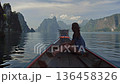 A traveler enjoys a serene moment on a traditional boat, surrounded by breathtaking limestone cliffs in Thailand. a woman in front of a longtail boat at Koh Hong Island in Krabi 136458326