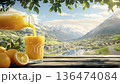 Orange juice pouring into glass with scenic mountain background and copy space 136474084