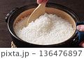 Freshly cooked rice cooked in a clay pot is loosened with a ladle. 136476897