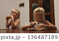 Little triplet sisters eating a burger in the kitchen 136487189