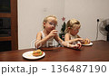 Little triplet sisters eating a burger in the kitchen 136487190