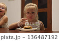 Little triplet sisters eating a burger in the kitchen 136487192