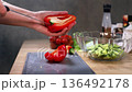 Preparing vegetables for a fresh salad at a kitchen counter with cutting board and bowls 136492178