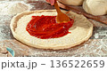 Super slow motion close-up of spreading tomato sauce on fresh pizza dough. Wooden spoon moves gently across the surface, highlighting texture, freshness and authentic Italian pizza preparation. 136522659