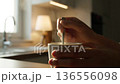 Close-up of hands stirring steaming hot coffee in a mug, cozy home setting. 136556098