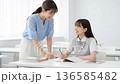 勉強を教える若い女性教師と笑顔の女子高生 136585482