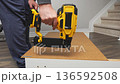 Handheld power tool is being used to fasten wood pieces together, showcasing the assembly process in a well-lit indoor workspace 136592508