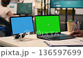 Blue screen on tablet and green screen on laptop in office workspace, black businessman focused on performance metrics and analytics, visual data, KPI reports and business intelligence. 136597699
