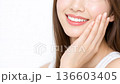 手で頬を触りスキンケアする笑顔の若い女性 136603405