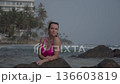 A girl in a red swimsuit on the coastal cliffs of the ocean 136603819