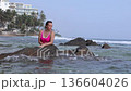 A girl in a red swimsuit on the coastal cliffs of the ocean 136604026