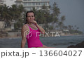 A girl in a red swimsuit on the coastal cliffs of the ocean 136604027